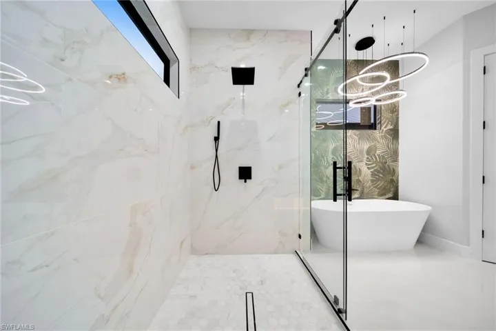 Spacious walk-in shower with a glass enclosure, white veined tile walls, and a hex tile floor