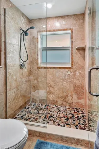Bathroom with a shower with shower door, tile patterned flooring, and toilet