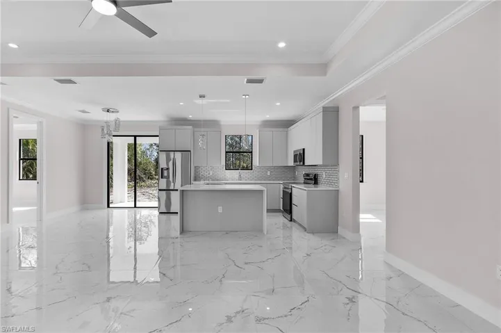 Kitchen featuring appliances with stainless steel finishes, gray cabinets, a kitchen island, tasteful backsplash, and light countertops