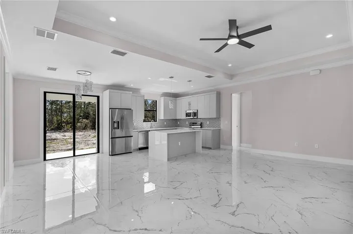 Kitchen with stainless steel appliances, ceiling fan, decorative backsplash, a kitchen island, and light countertops