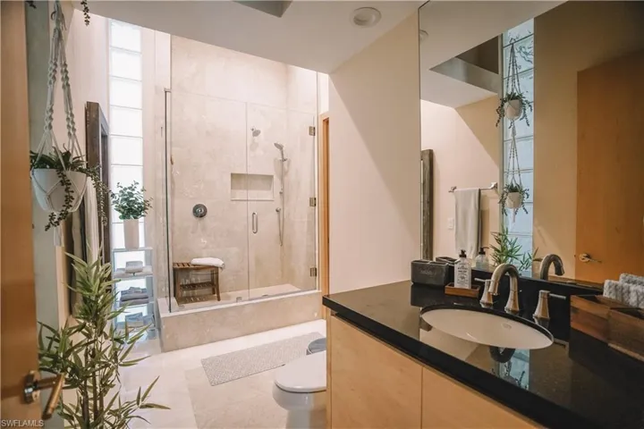 Bathroom featuring vanity, toilet, an enclosed shower, and tile patterned floors