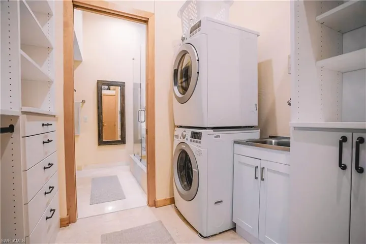Laundry area with light tile patterned floors and stacked washer / drying machine