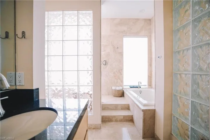Bathroom featuring tiled tub, tile patterned floors, and a wealth of natural light
