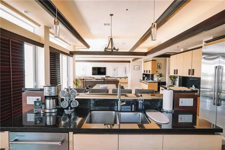Kitchen featuring pendant lighting, sink, white cabinets, and high quality fridge