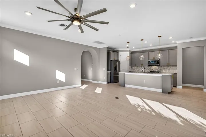 Unfurnished living room with arched walkways, recessed lighting, a ceiling fan, and ornamental molding