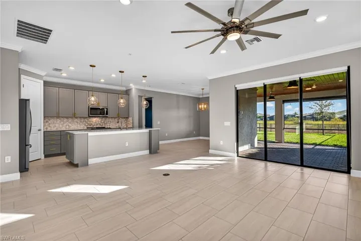Unfurnished living room with ceiling fan, ornamental molding, recessed lighting, a chandelier, and wood tiled floors