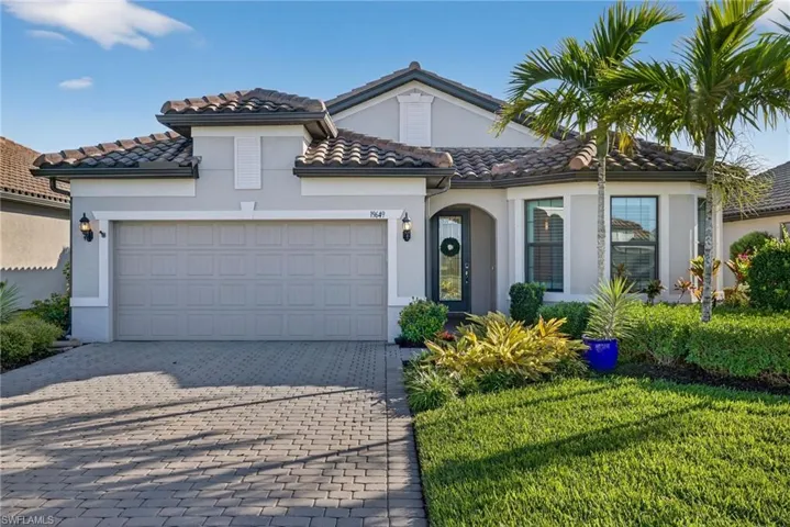 Mediterranean / spanish-style home with decorative driveway, stucco siding, a front yard, a garage, and a tile roof