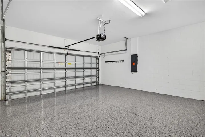 Garage with concrete block wall, electric panel, and a garage door opener