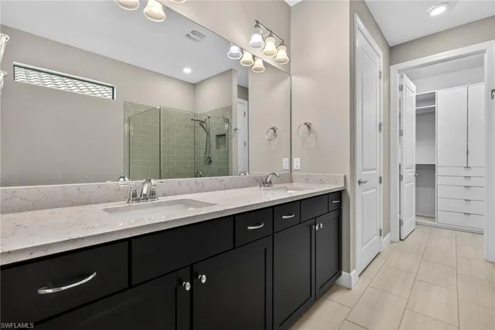 Full bath with a shower stall, double vanity, a spacious closet, and recessed lighting