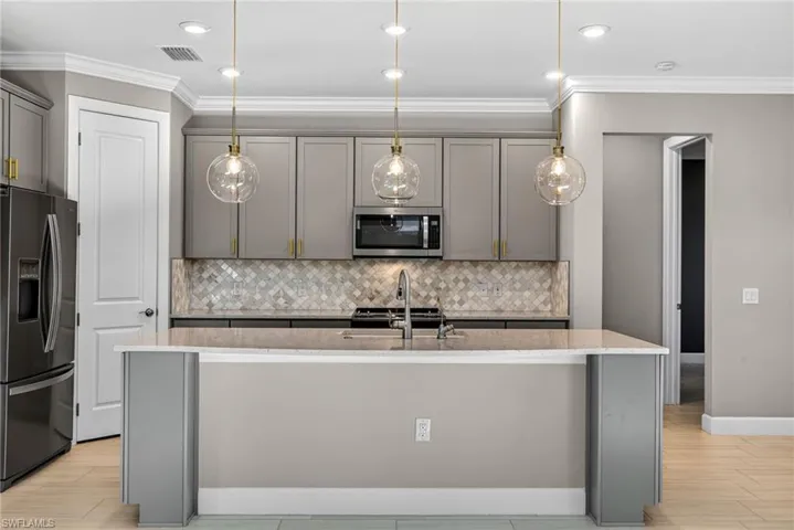Kitchen featuring gray cabinets, black refrigerator with ice dispenser, light stone countertops, and crown molding
