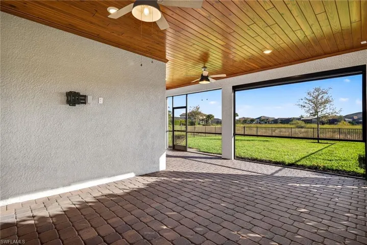 Unfurnished sunroom featuring ceiling fan, a patio area, and a residential view
