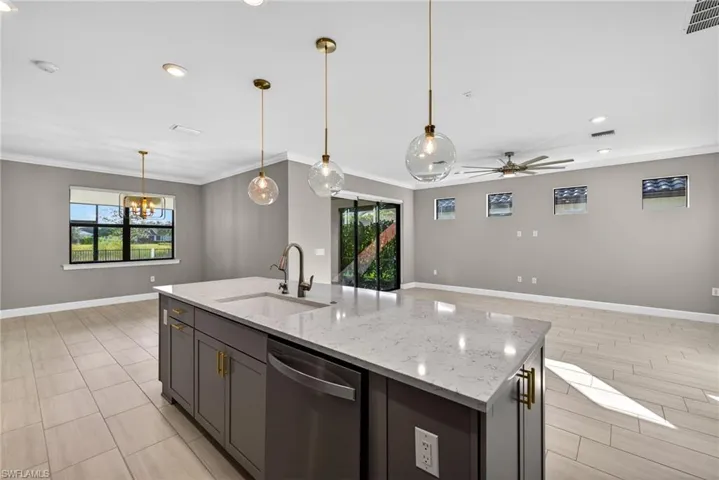 Kitchen featuring dishwasher, decorative light fixtures, recessed lighting, light stone counters, and a center island with sink