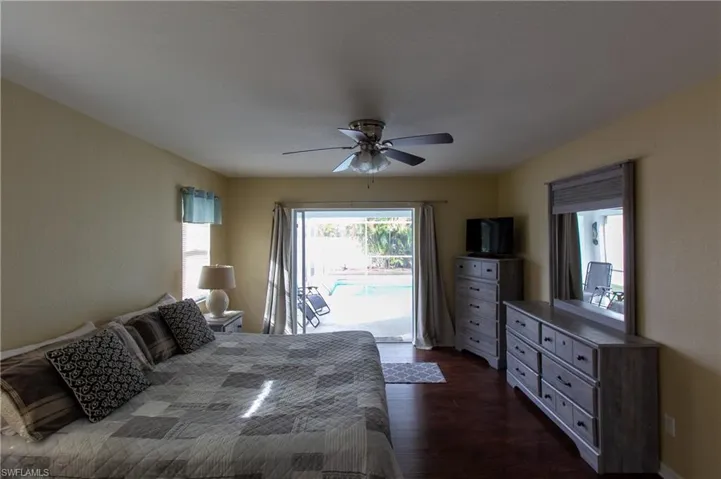 Bedroom with ceiling fan, dark hardwood / wood-style flooring, and access to exterior