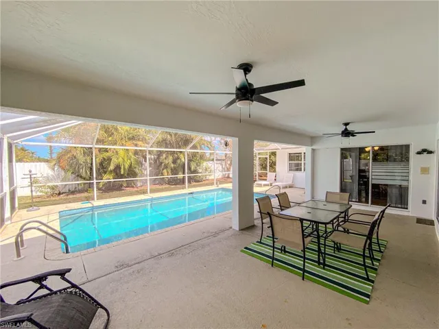 View of pool featuring a patio, ceiling fan, and glass enclosure