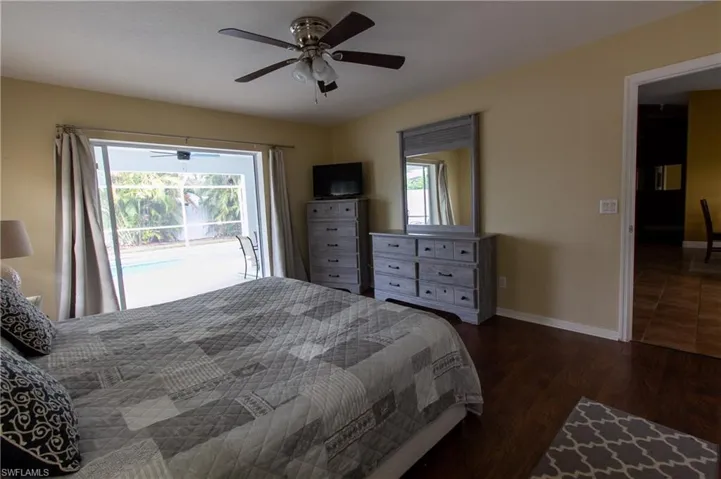 Bedroom featuring ceiling fan, multiple windows, access to exterior, and dark hardwood / wood-style flooring