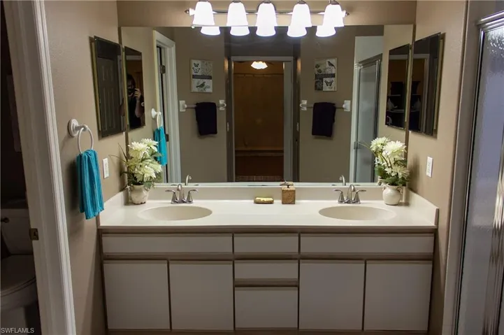 Bathroom featuring vanity, toilet, and a shower