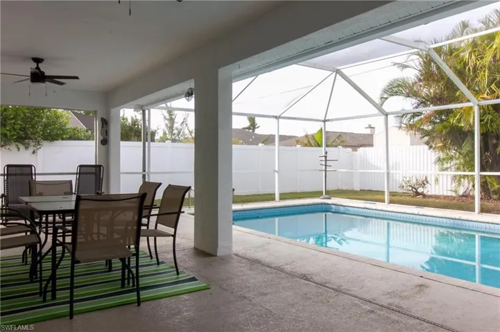 View of swimming pool with a patio, glass enclosure, and ceiling fan