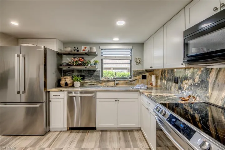 Kitchen featuring light hardwood / wood-style flooring, tasteful backsplash, stainless steel appliances, sink, and white cabinets