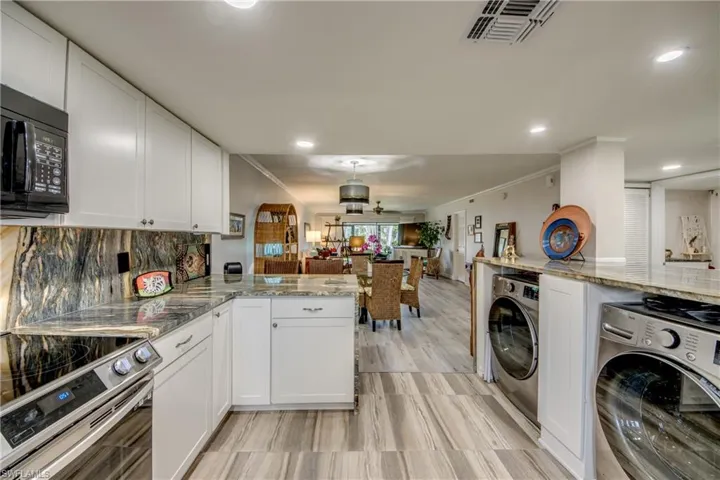 Kitchen featuring white cabinetry, tasteful backsplash, washer / dryer, and kitchen peninsula