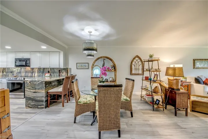 Dining area with ornamental molding and light hardwood / wood-style flooring