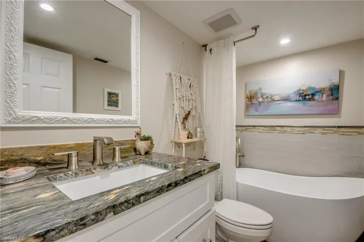 Bathroom with vanity with extensive cabinet space and toilet
