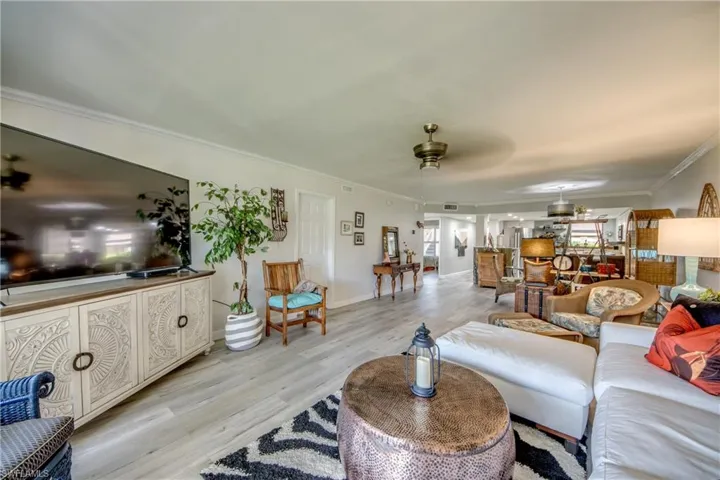 Living room with crown molding, ceiling fan, and light hardwood / wood-style flooring