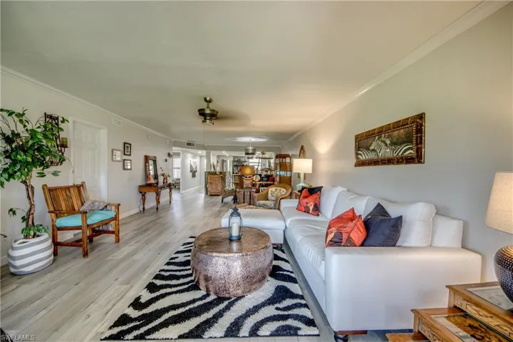 Living room with ceiling fan, light hardwood / wood-style floors, and ornamental molding