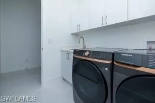 Clothes washing area with washer and dryer, cabinets, sink, and hookup for a washing machine