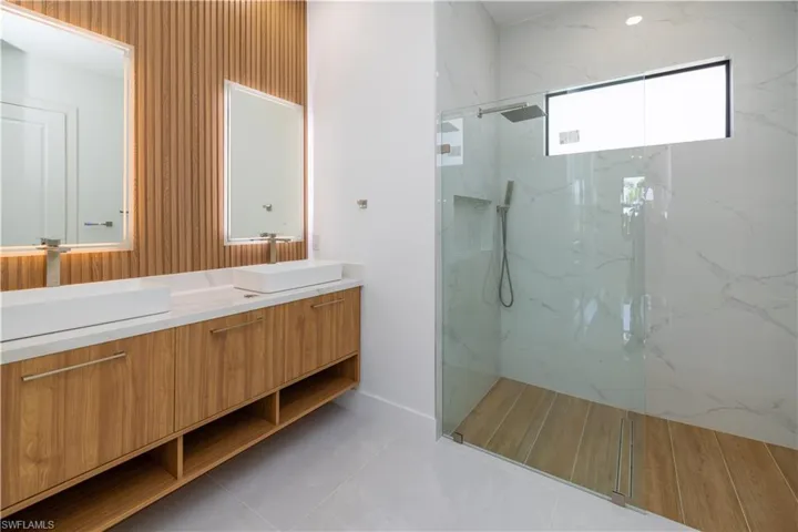Bathroom featuring a tile shower, vanity, and tile floors