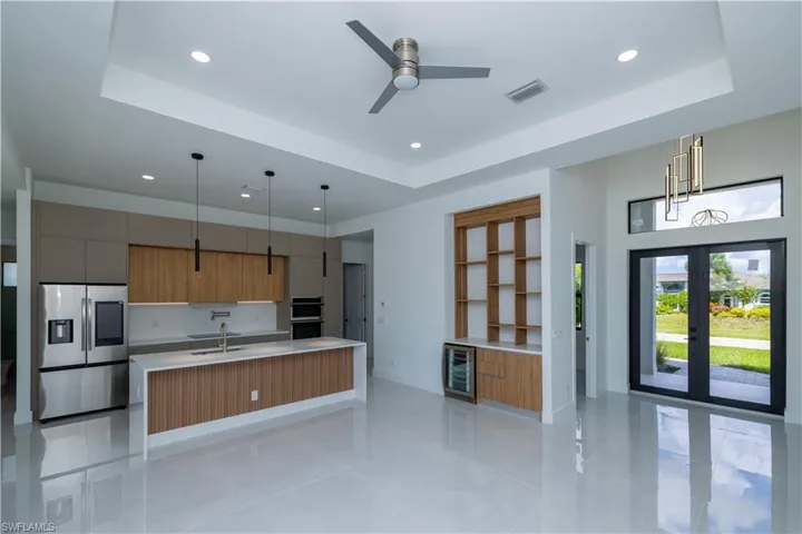 Kitchen featuring wine cooler, a raised ceiling, stainless steel appliances, and a center island with sink