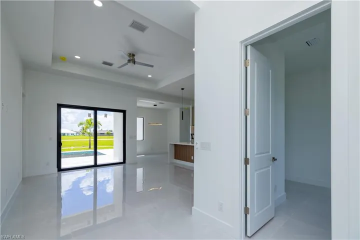 Unfurnished room with tile flooring, ceiling fan, and a tray ceiling
