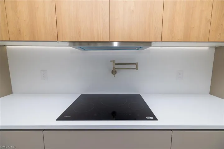 Details with exhaust hood, black electric cooktop, and light brown cabinetry