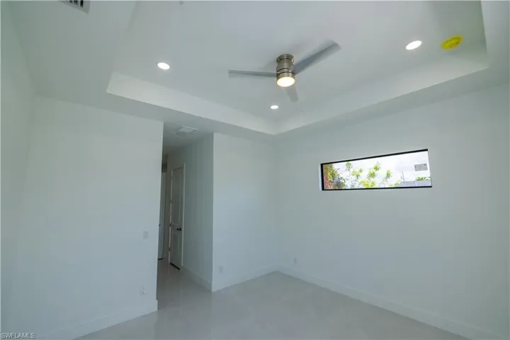 Tiled spare room featuring ceiling fan and a raised ceiling