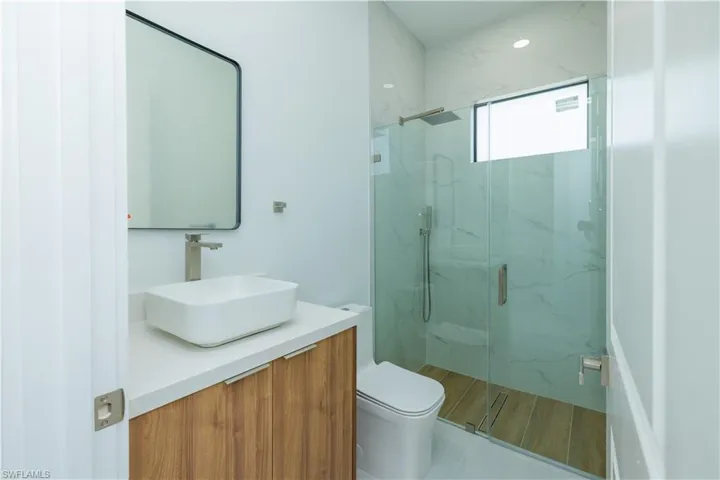 Bathroom featuring tile floors, an enclosed shower, vanity, and toilet