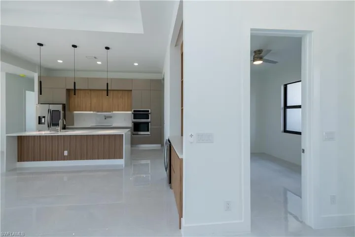 Kitchen with ceiling fan, a center island with sink, decorative light fixtures, light tile floors, and appliances with stainless steel finishes