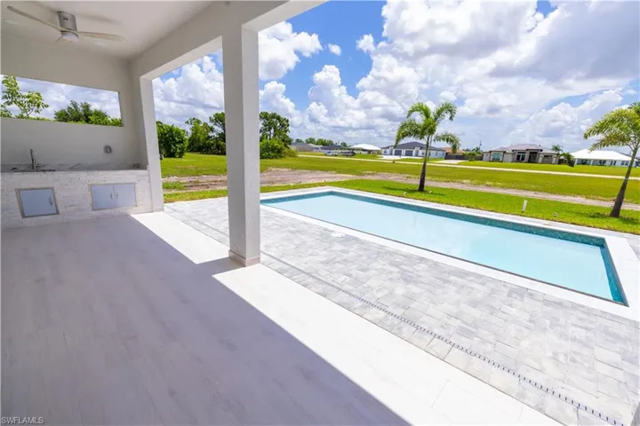 View of swimming pool with ceiling fan, a lawn, and a patio area