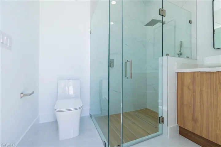 Bathroom with tile flooring, an enclosed shower, toilet, and vanity