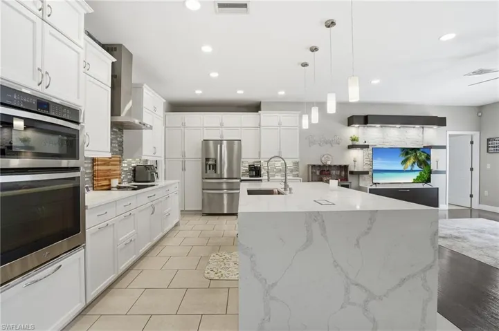 Beautiful kitchen with waterfall island, sleek tile backsplash, and plenty of cabinets