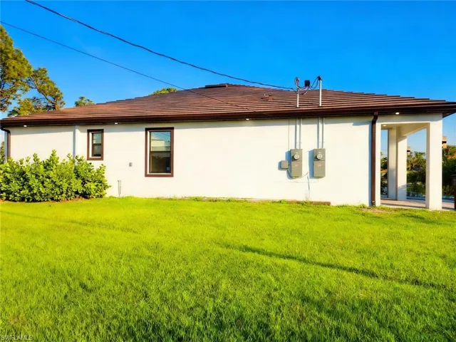 Rear view of property with a lawn and stucco siding