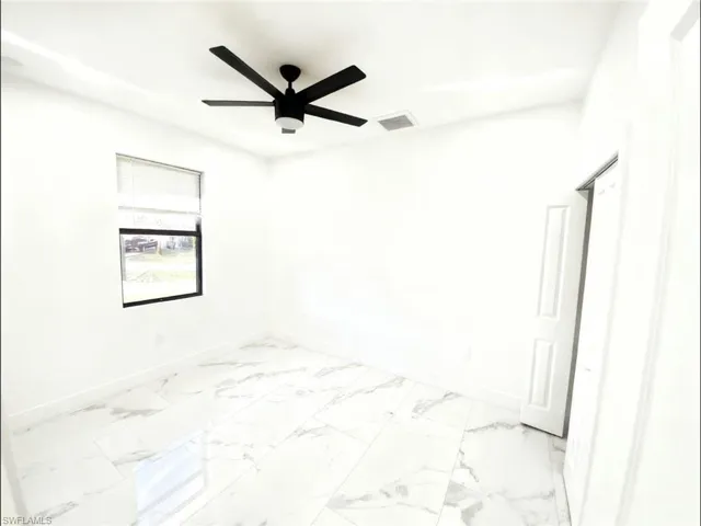Unfurnished room with a ceiling fan and light marble finish floors