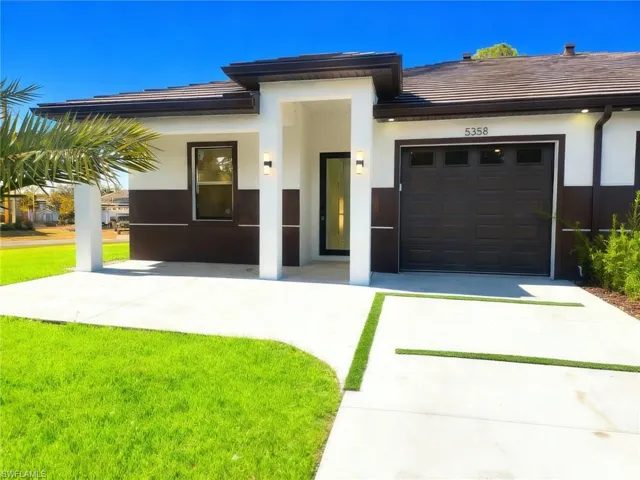 View of front of house with stucco siding, concrete driveway, and a garage