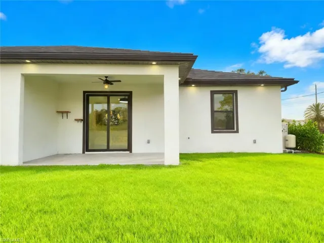Back of property featuring a patio area, a yard, and stucco siding