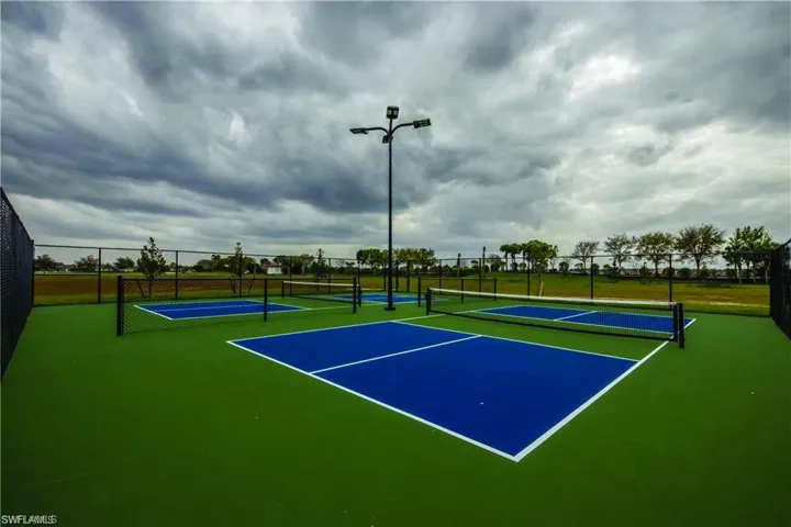Multiple pickleball courts with vibrant blue playing surfaces and green surrounds