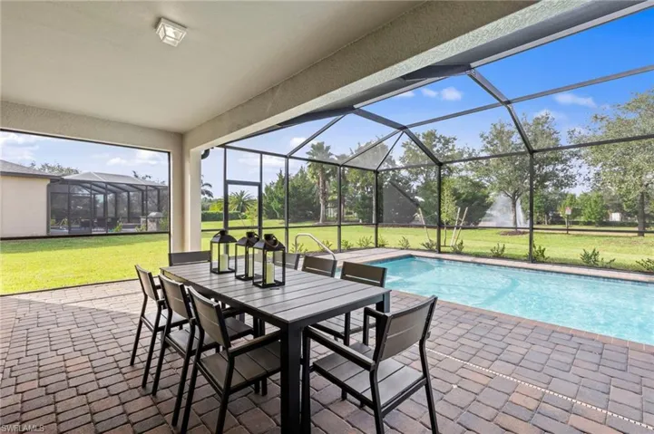 Screened patio featuring a paver deck, a rectangular swimming pool, and a fountain feature in the background