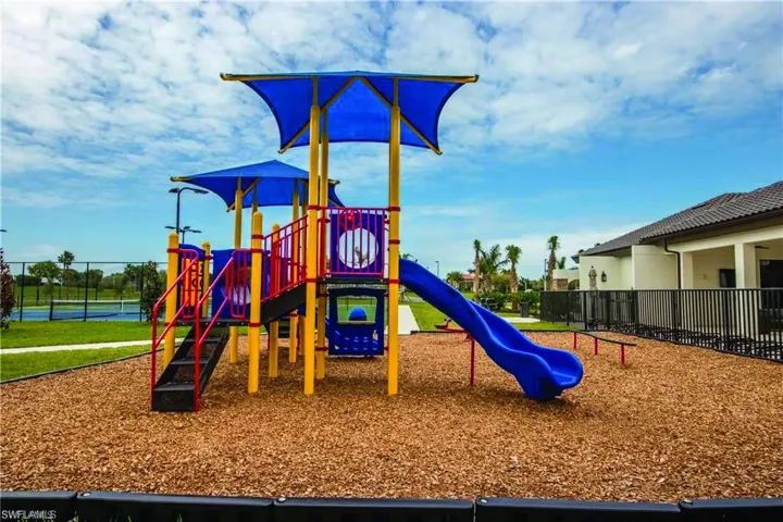 Community play structure featuring a slide, climbing elements, and shade canopies