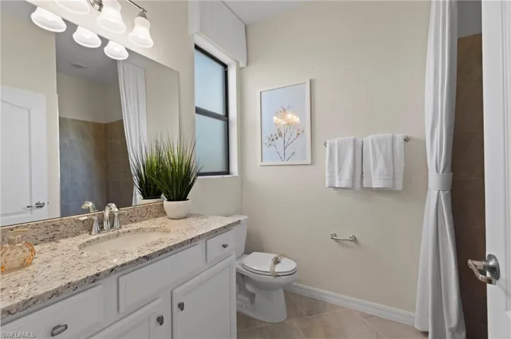 Bathroom featuring a light-toned vanity with a speckled countertop, an undermount sink, and chrome fixtures