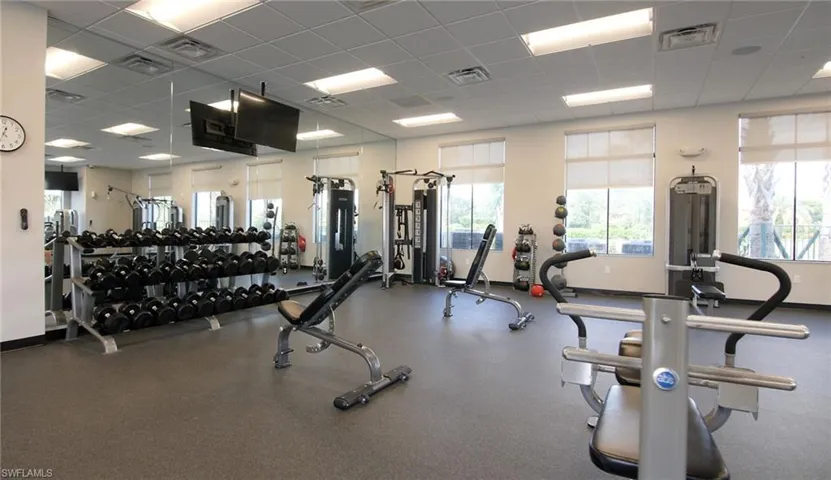 Fitness center featuring full-height mirrors, ample natural light, recessed ceiling lights, and rubber flooring