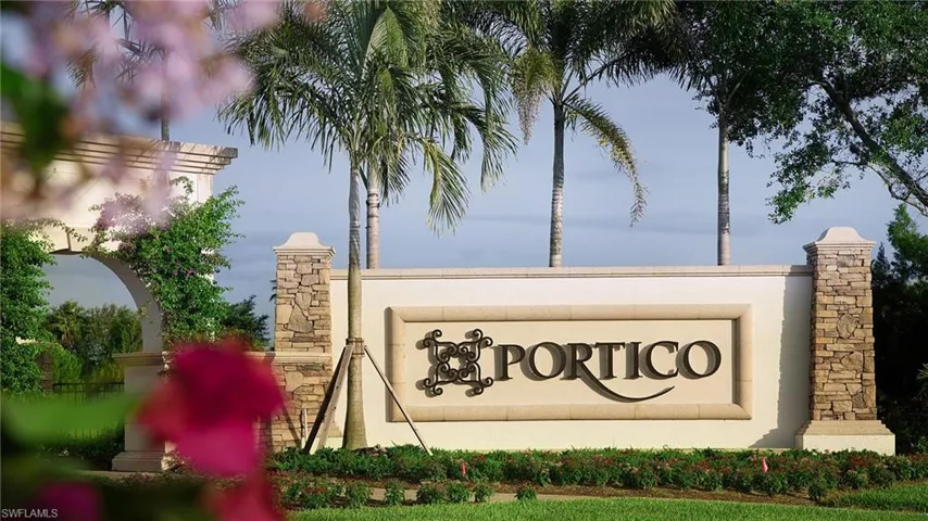 Community entrance signage featuring stacked stone accents, mature palm trees, and lush landscaping