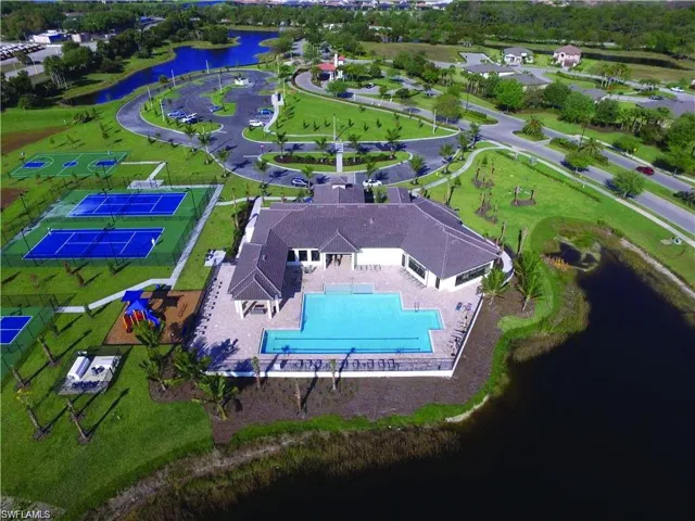 Community clubhouse featuring an expansive swimming pool with a surrounding paver deck, multiple tennis courts, and a playground area
