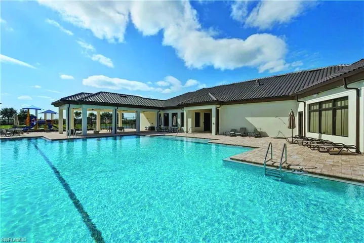Large outdoor swimming pool with integrated metal ladders, surrounded by a paver deck